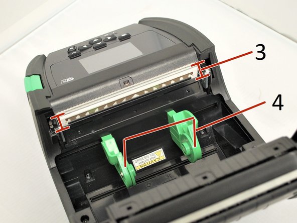 To open the printer, press down on the green media cover release button on the right side of the printer. The lid is spring loaded, and should pop open.