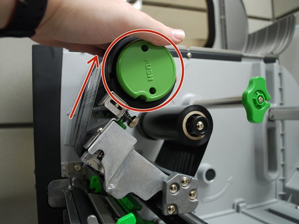 Tightly wind the ribbon around the ribbon rewind spindle until taut - it has a black plastic surface and a green cap that says &quot;PUSH.&quot;