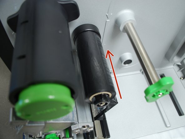 Place the roll of ribbon on the ribbon spindle - the black plastic spindle located a little bit above and behind the print head.