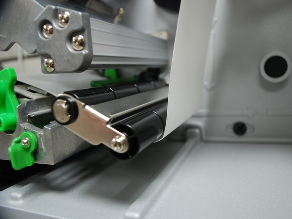 Feed the labels through/under the green media sensor bar (blue arrow in the picture).