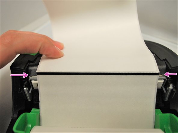 Pull the leading edge of the labels down, past the front of the printer. The black mark between labels should face upwards, and the actually labels should be face-down, facing the printhead.