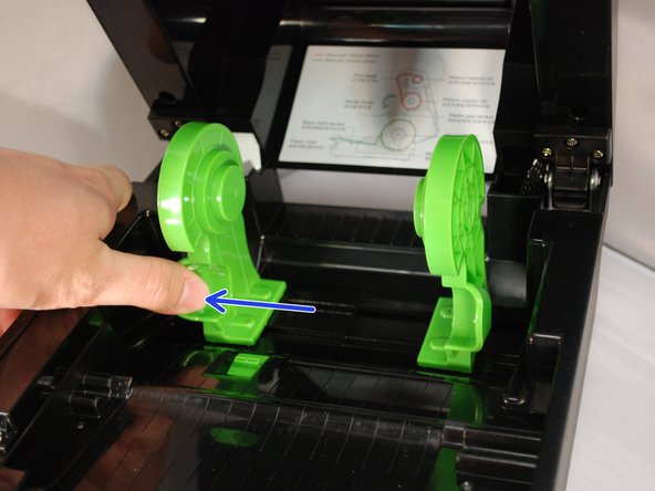 Open the printer's top cover by using a finger to pull forward (towards the front of the printer) on each of the green releases latches, located on either side of the printer. Lift the top cover until fully opened.