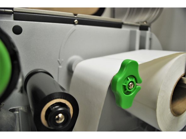 Feed the labels over the media guide bar, and under the damper roller.