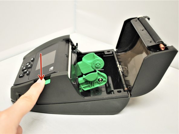 Make sure the printer is turned off, then open the cover by pressing the green Media Cover Release Button.