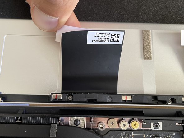 Peel away the white backing liner on one of the black grounding pads and stick the pad onto the Top Cover.