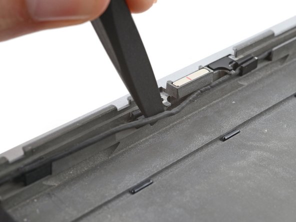 Slide the speaker cable out from under its screw hole peg in the frame.