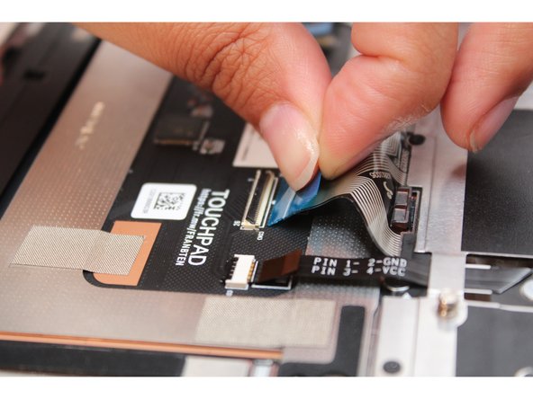 Grip the blue pull tab and connect the Keyboard Membrane cable into the Touchpad. Make sure the black latch is flipped up so that you can slide the cable into the connector.