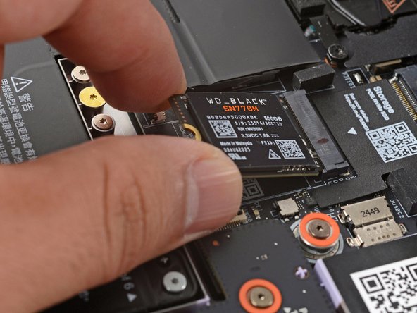 Grab the SSD by its edges and pull it out of its socket.