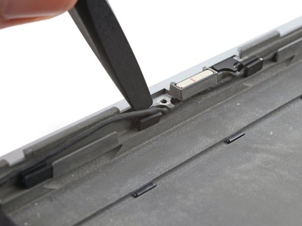 Slide the speaker cable out from under its screw hole peg in the frame.