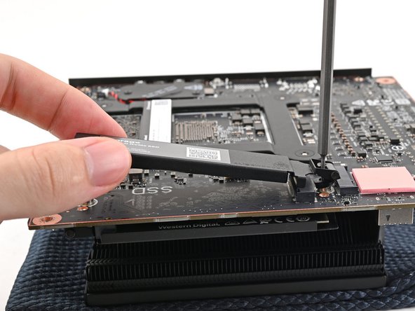 While securing the secondary storage heat spreader with one hand, use your Framework Desktop Screwdriver to remove the 4.5 mm‑long T5 Torx screw securing it.
