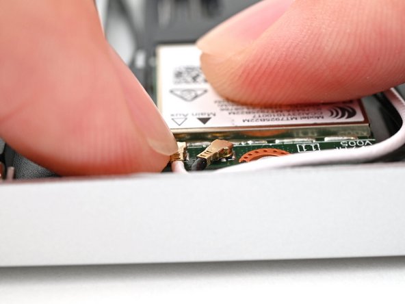 Position the black antenna cable connector over the Wi-Fi module's coaxial socket indicated by the black arrow.