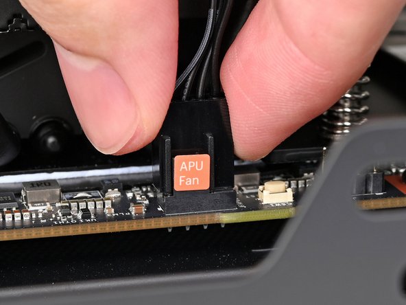 Slide the main fan cable over the four-pronged connector labeled &quot;APU Fan,&quot; making sure the orange label slots between the vertical lines.