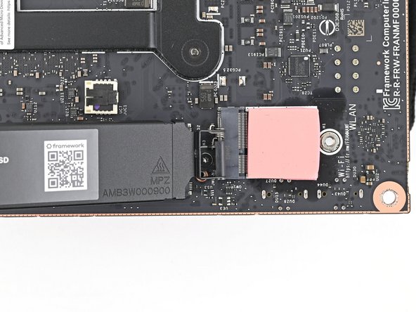 While securing the secondary storage heat spreader with one hand, use your Framework Desktop Screwdriver to remove the 4.5 mm‑long T5 Torx screw securing it.