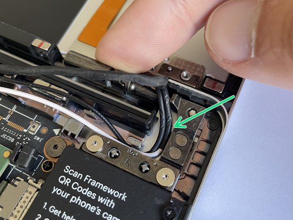 Route the antenna cables through the hinge area, with the white and black cables sitting flat against the bottom of the Bottom Cover as much as possible.  Avoid letting the cables twist or overlap, as this will interfere with the Input Cover and power button.  You can use the spudger end of the Framework Screwdriver to help push the cables.