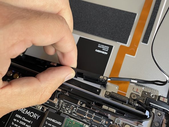 Pull the Antenna Module up and away, peeling the black grounding stickers off of the Top Cover with them.  Note that the adhesive may be strong, and it is ok if a little residue is left on the Top Cover afterwards.