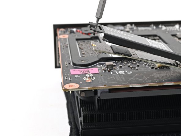 Insert your Framework Desktop Screwdriver into the captive screw on the secondary storage heat spreader and press it flat to the Mainboard.