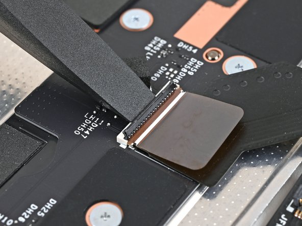 Use the flat end of your Framework Screwdriver, or a clean fingernail, to press down the locking tab on the Mid Plate Cable ZIF connector.