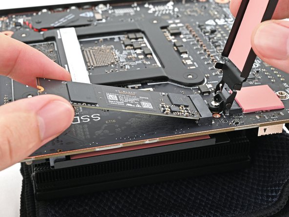 While holding the heat spreader upright, align the SSD's gold contacts with its socket.