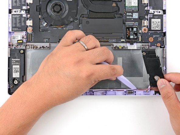Use your Framework Screwdriver to lift and guide the wire connecting the two speakers out of the frame channel.