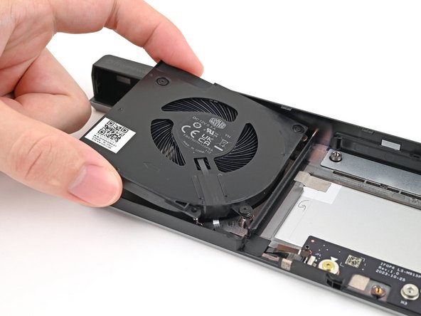 Place the left fan onto the Expansion Bay Shell, making sure to thread the cable through its slot.