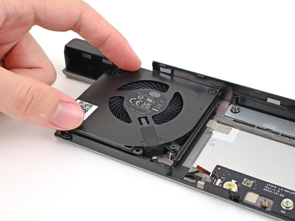 Place the left fan onto the Expansion Bay Shell, making sure to thread the cable through its slot.