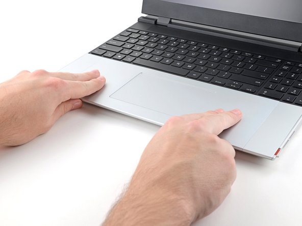 Use your fingers to slide the Touchpad Module toward the bottom edge of the laptop and disconnect it.