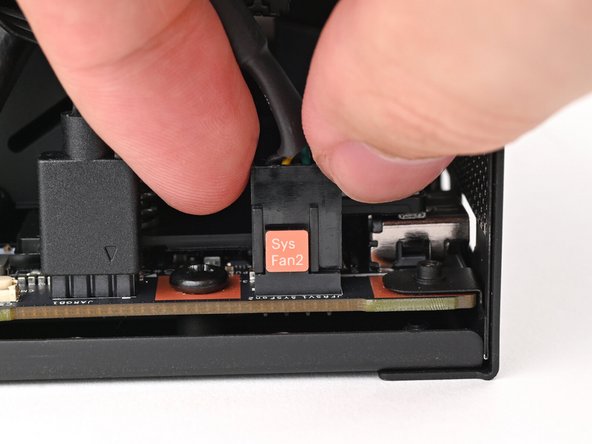 Slide the fan cable over the four-pronged connector labeled "Sys Fan 2," making sure the orange label slots between the vertical lines.