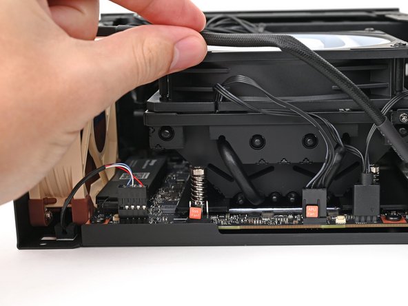 Move the fan cable underneath the heat sink and tuck it behind the silver screw post.