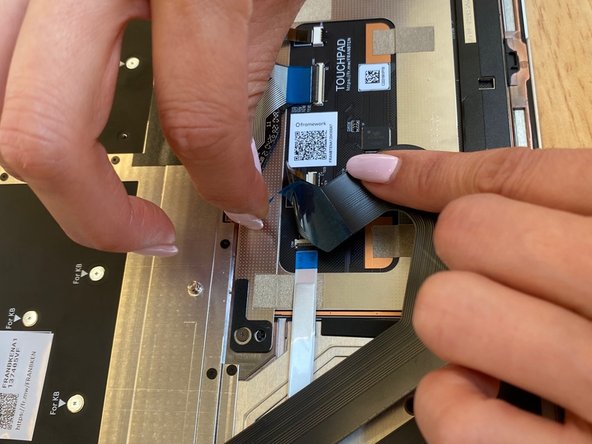 Gently peel off the blue film on the underside of the Touchpad cable as shown in the first image.