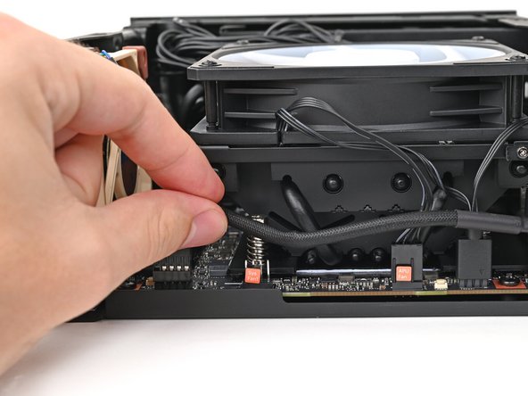 Move the fan cable underneath the heat sink and tuck it behind the silver screw post.