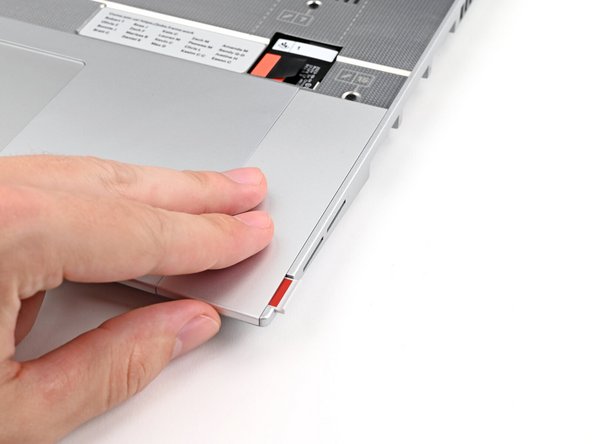 Use your fingers to slide the Touchpad Spacer toward the bottom edge of the laptop and unclip it.