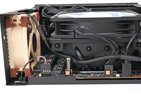 Move the fan cable underneath the heat sink and tuck it behind the silver screw post.