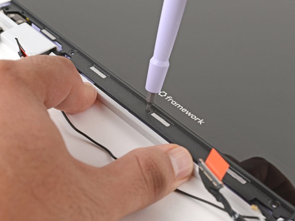 Insert the bit end of your Framework Screwdriver into the small hole on the display, below the Framework logo.