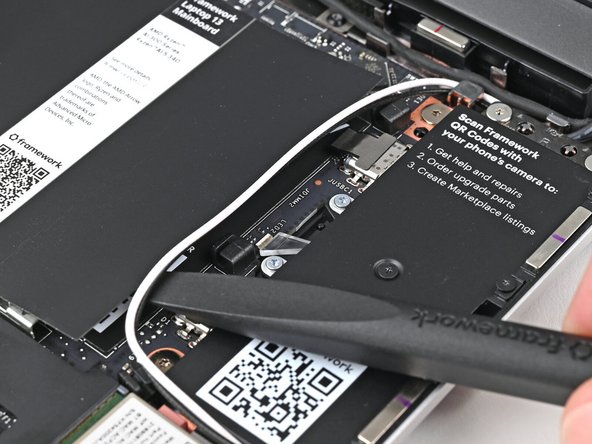 Use your fingers or the flat end of the Framework Screwdriver to lift the two Antenna Cables out of their clips on the Mainboard.