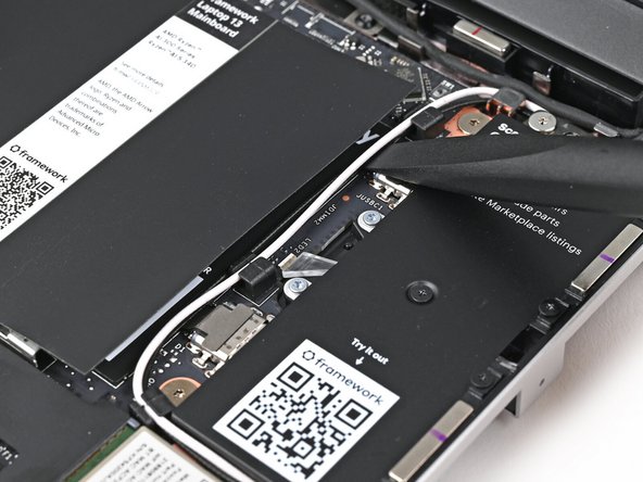 Use your fingers or the flat end of the Framework Screwdriver to lift the two Antenna Cables out of their clips on the Mainboard.