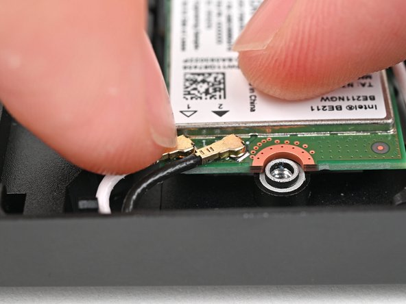 Position the black antenna cable connector over the left Wi-Fi module's coaxial socket.