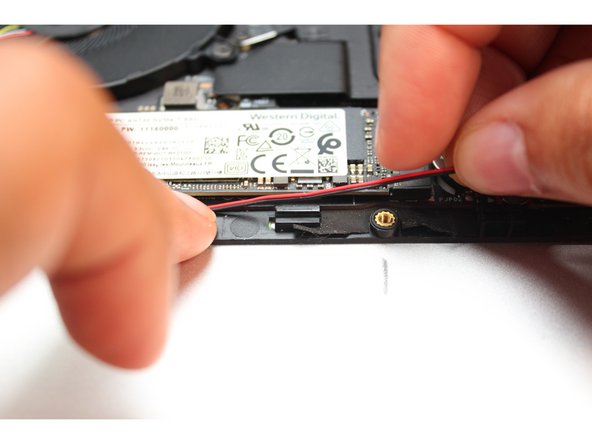 Place the wires into the wire router next to the other piece of black tape.  Peel the tape back and place the wires under it. Cover the wires with same tape.