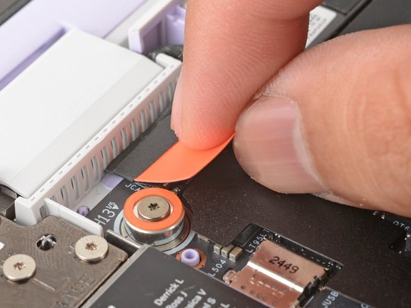 Use your fingers to grab the orange tab on the webcam cable, located near the left hinge.