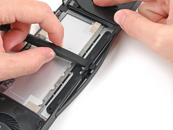 While holding the Expansion Bay Shell down, use the flat end of your Framework Screwdriver to push the plastic strip near the rubber spacer outwards.