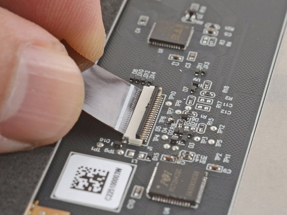 Grab the touchpad cable by the brown tab and slide it out of its connector.