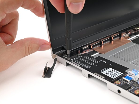 While supporting the Top Cover with one hand, use your Framework Screwdriver to remove two 4.0 mm‑long T5 Torx screws on each Hinge connected to the Bottom Cover (four total).