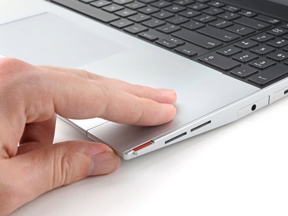 Use your fingers to slide the Touchpad Spacer toward the bottom edge of the laptop and unclip it.