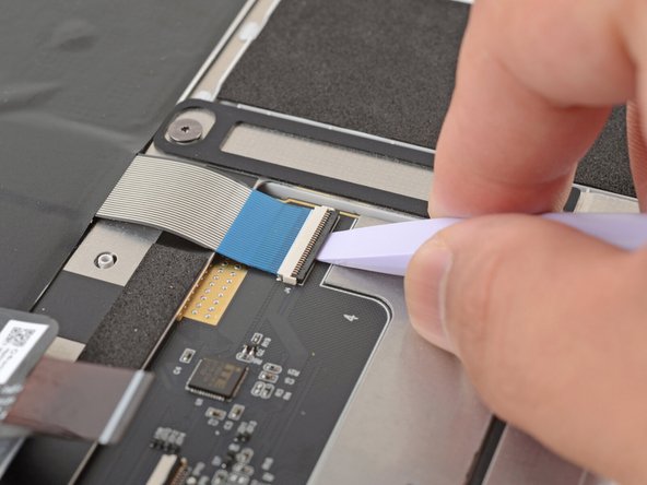 Use the flat end of your Framework Screwdriver or a fingernail to gently pry up the black locking tab on the keyboard cable ZIF connector, located on the back of the touchpad.