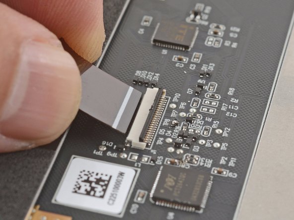 Grab the touchpad cable by the brown tab and slide it out of its connector.