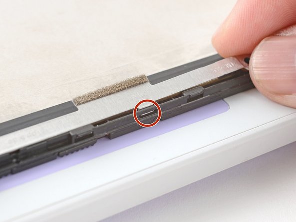 Make sure the tabs on the top edge of the webcam bracket sit in their slots on the top edge of the display.