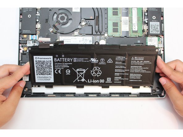 Using your fingertips, gently handle the Framework battery with the plastic frame, slide it into the Bottom Cover.  Use the first image as a reference.