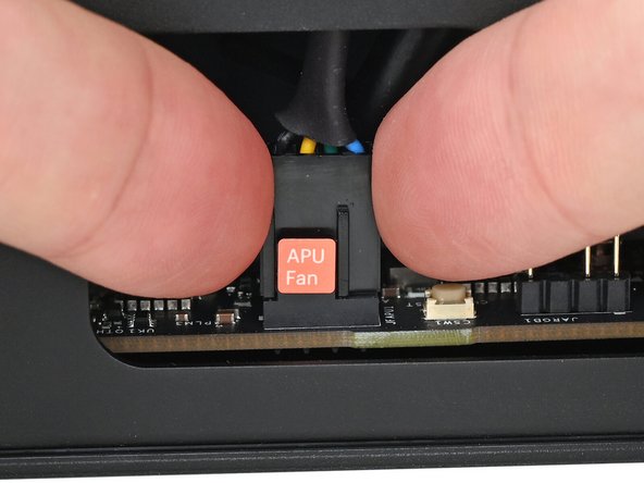 Slide the main fan cable over the four-pronged connector labeled &quot;APU Fan,&quot; making sure the orange label slots between the vertical lines.