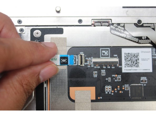 Connect the other end of the Fingerprint Cable into the Touchpad Module. Make sure the black latch is flipped up so that you can slide the cable into the connector.
