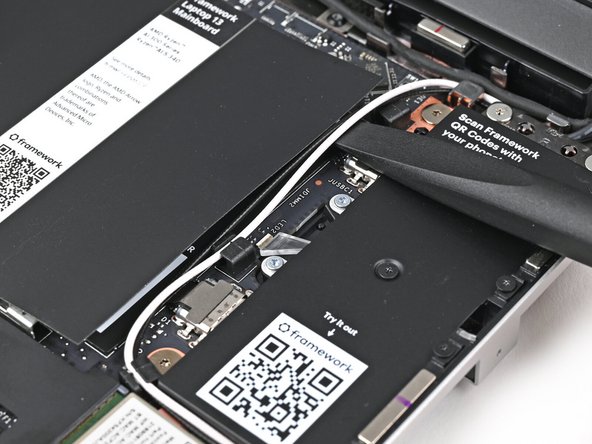 Use the flat end of the Framework Screwdriver to lift the two antenna cables out of their rubber clips on the Mainboard.