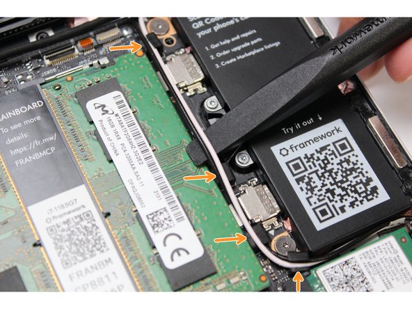 Using the spudger end of the Framework Screwdriver, release the black and white WiFi Antenna cables by gently lifting them out from the rubber holders.